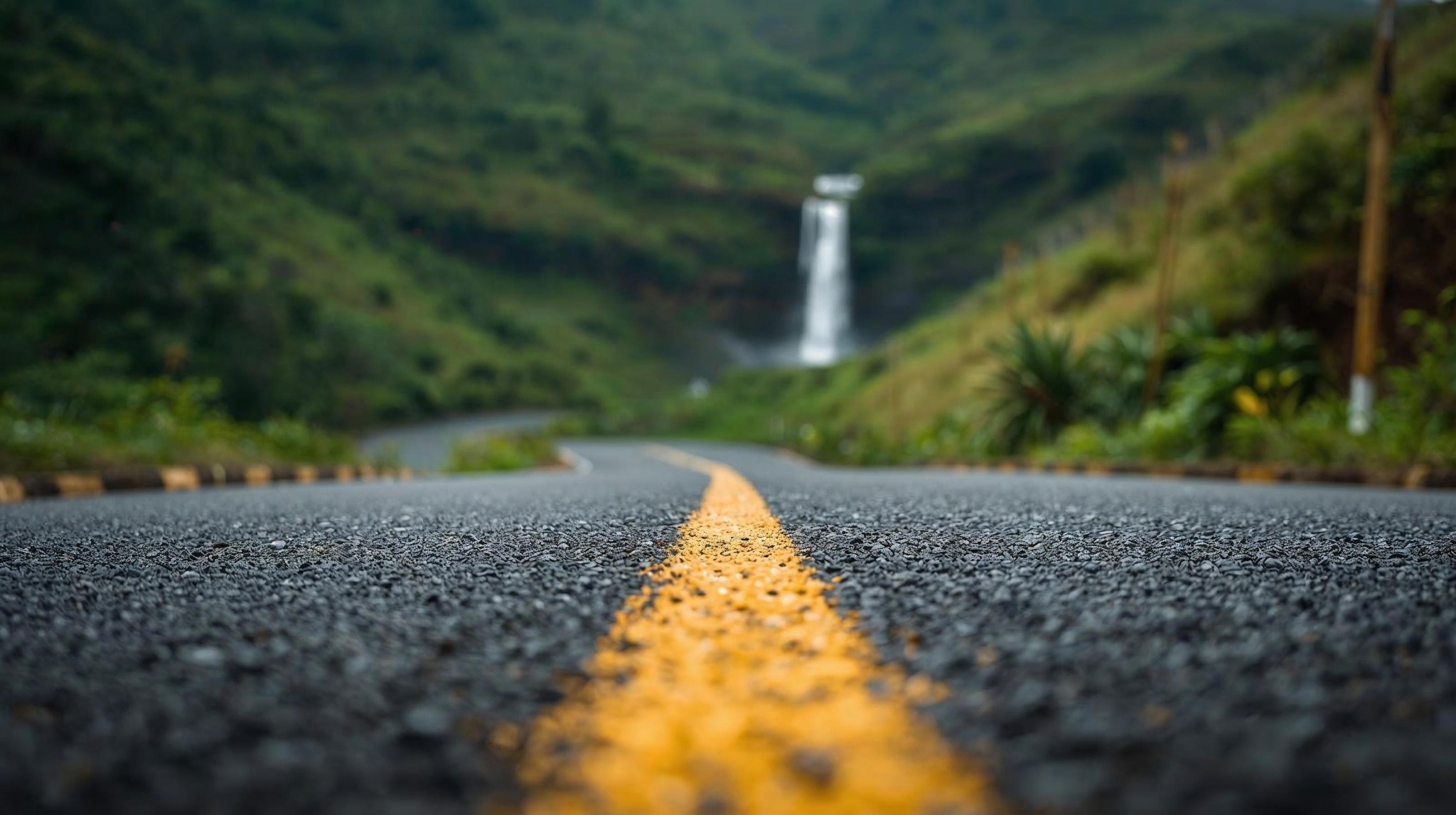 Scenic road in Sri Lanka hill country leading toward a distant waterfall